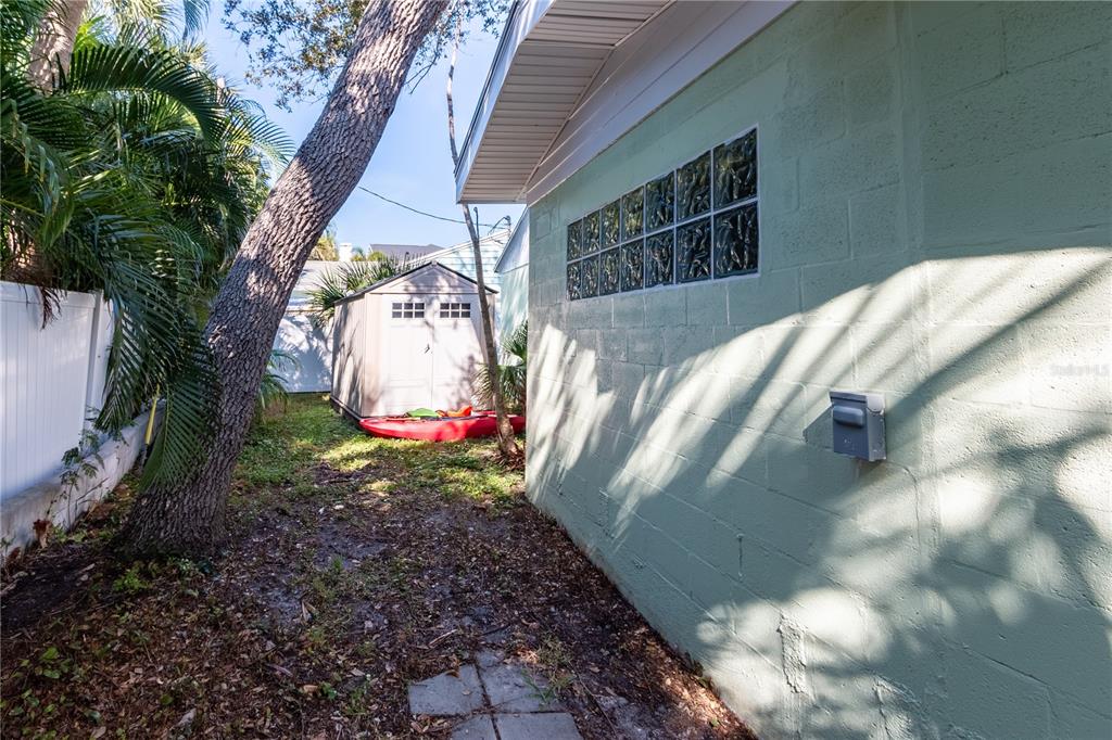 A side view of a light green concrete block house with glass block windows and shed — 750 BAY ESPLANADE, CLEARWATER BEACH, FL
