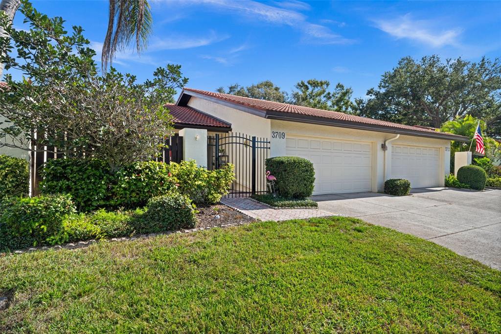 A single-story house with a two-car garage, gated entryway, and landscaped front yard — 3709 MIGUEL WAY UNIT 8602, SARASOTA, FL