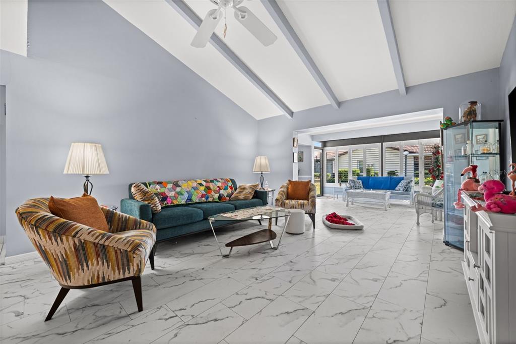 A living room features vaulted ceilings, marble-look tile flooring, and a teal sofa — 3709 MIGUEL WAY UNIT 8602, SARASOTA, FL