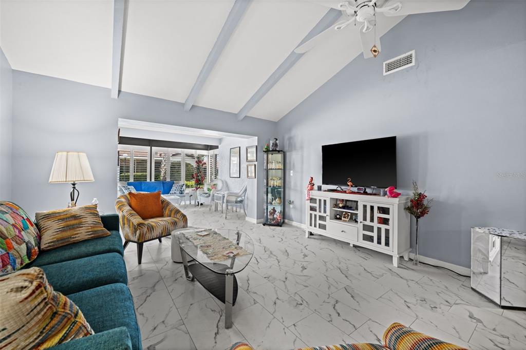 A living room features vaulted ceilings, white marble-look tile floors, and a television console — 3709 MIGUEL WAY UNIT 8602, SARASOTA, FL