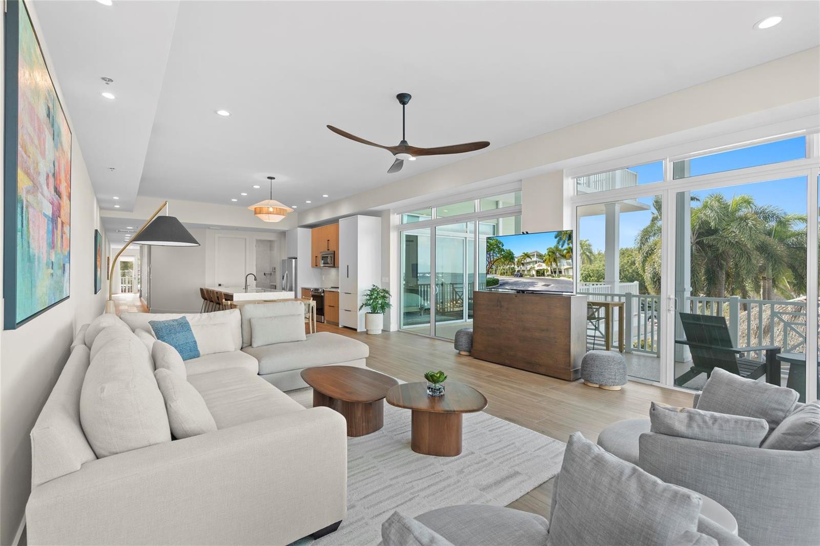 A modern living room features a sectional sofa, wooden coffee tables, and large glass sliding doors — 104000 Overseas Highway, Key Largo FL 33037, KEY LARGO, FL