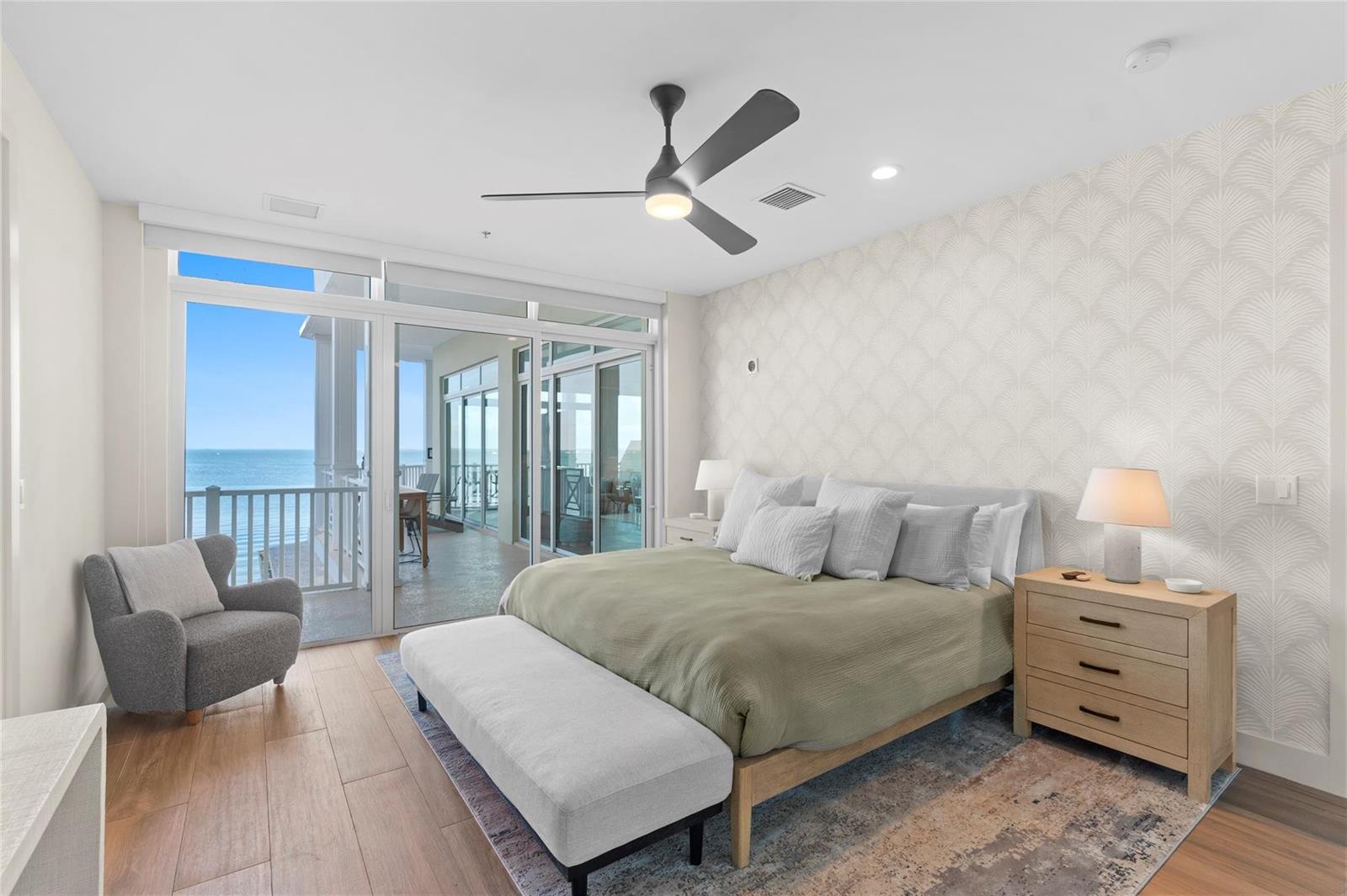 A bedroom with a king bed, gray armchair, and sliding glass doors overlooking the ocean — 104000 Overseas Highway, Key Largo FL 33037, KEY LARGO, FL