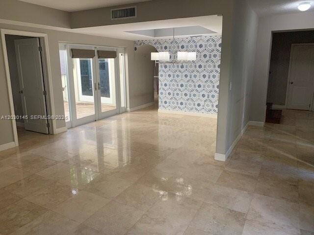 An open-concept dining area features light-colored tile flooring and a geometric patterned accent wall — 423 Alhambra Cir, Coral Gables FL 33134, CORAL GABLES, FL