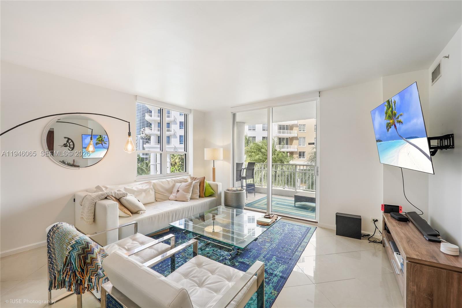 A living room features a white sofa, glass coffee table, blue rug, and a wall-mounted television — 701 Brickell Key Blvd # 404, Miami FL 33131, MIAMI, FL