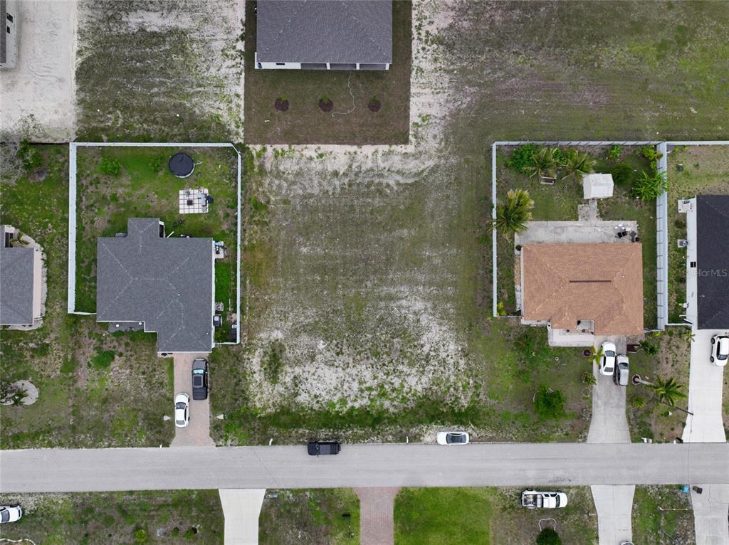 An aerial view shows a vacant residential lot situated between two existing houses — 530 NW 23RD TERRACE, CAPE CORAL, FL