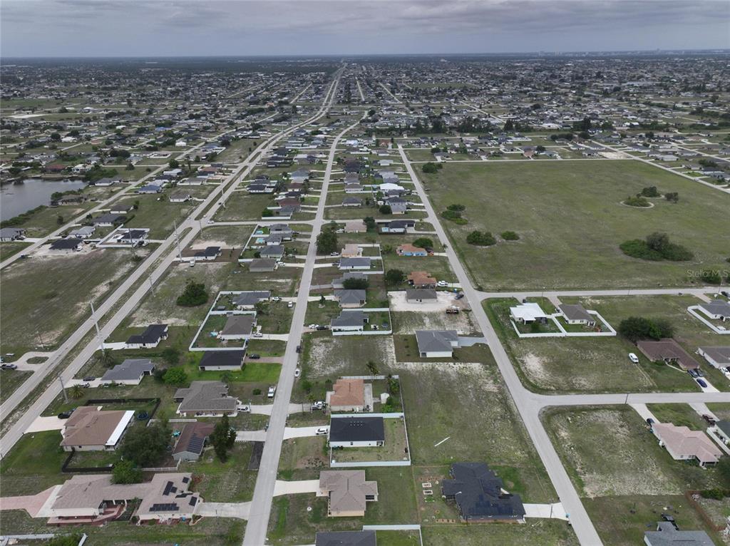 An aerial view shows a suburban neighborhood with scattered houses and large undeveloped grassy lots — 530 NW 23RD TERRACE, CAPE CORAL, FL