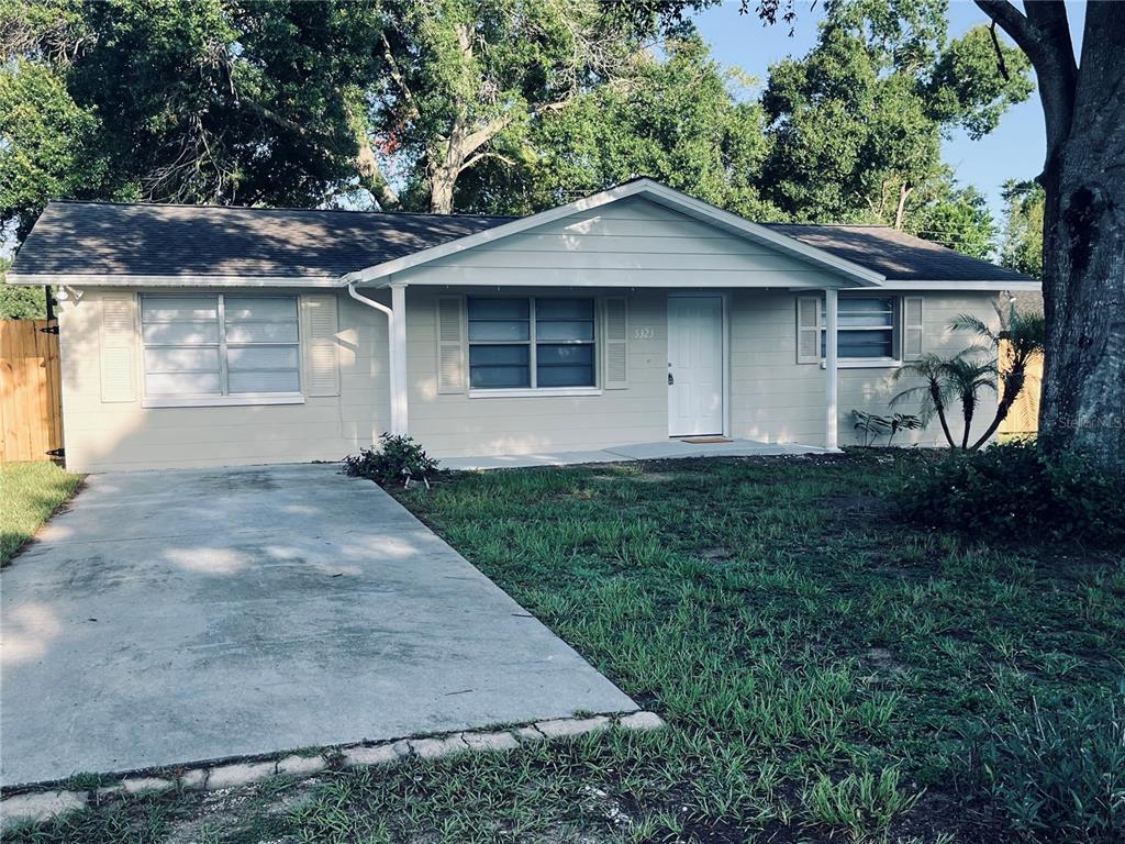 A single-story house with light-colored siding, a concrete driveway, and a covered front porch — 5323 SATSUMA DRIVE, ZEPHYRHILLS, FL