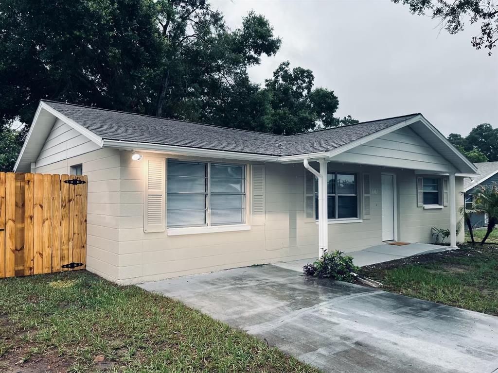 A single-story house with light-colored siding, a concrete driveway, and a wooden privacy fence — 5323 SATSUMA DRIVE, ZEPHYRHILLS, FL