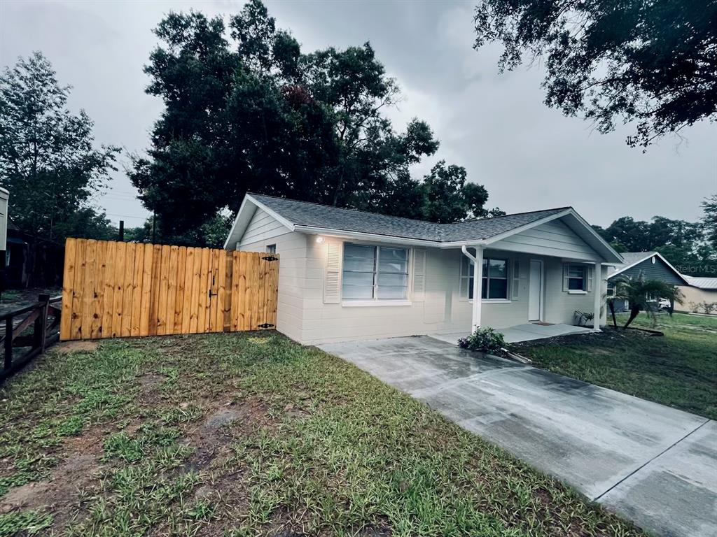 A single-story house with a light-colored exterior, a concrete driveway, and a wooden privacy fence — 5323 SATSUMA DRIVE, ZEPHYRHILLS, FL