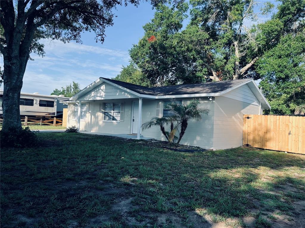 A light-colored, single-story house with a wooden fence and a large tree in the yard — 5323 SATSUMA DRIVE, ZEPHYRHILLS, FL