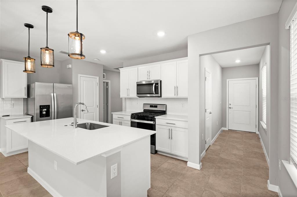 A modern kitchen features white cabinets, stainless steel appliances, and a large central island — 44201 KELLY DRIVE, PUNTA GORDA, FL