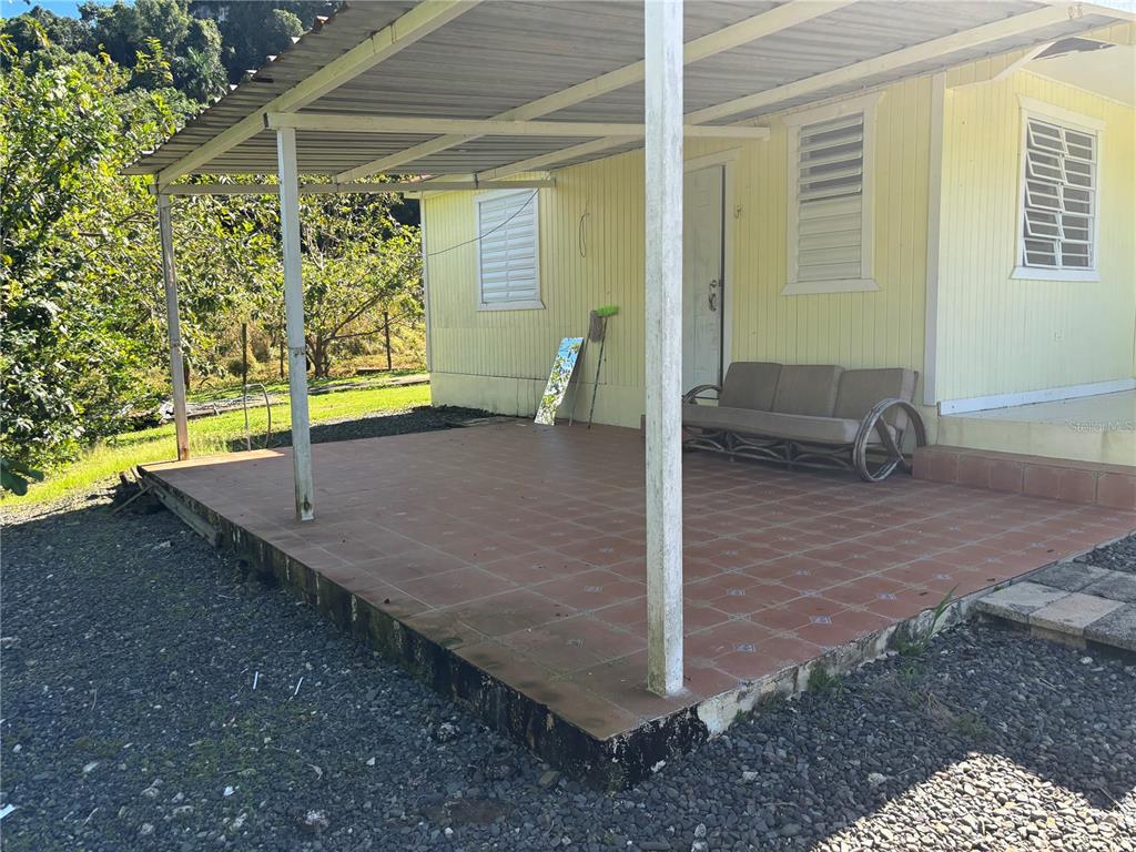 A yellow house features a covered patio with tiled flooring and a sofa — 14 PR-146 FRONTON, CIALES, PR