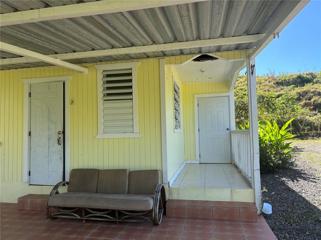 A yellow house exterior features a covered porch, a sofa, and two white doors — 14 PR-146 FRONTON, CIALES, PR
