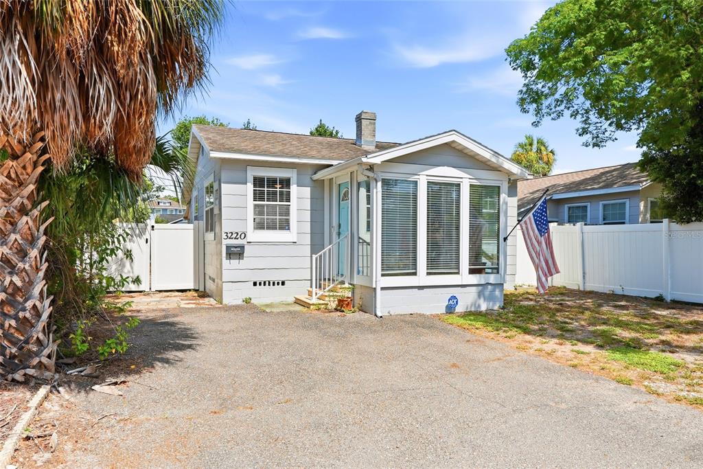 A small, light-gray house with a front porch, large windows, and a paved driveway — 3220 16TH STREET N, ST PETERSBURG, FL