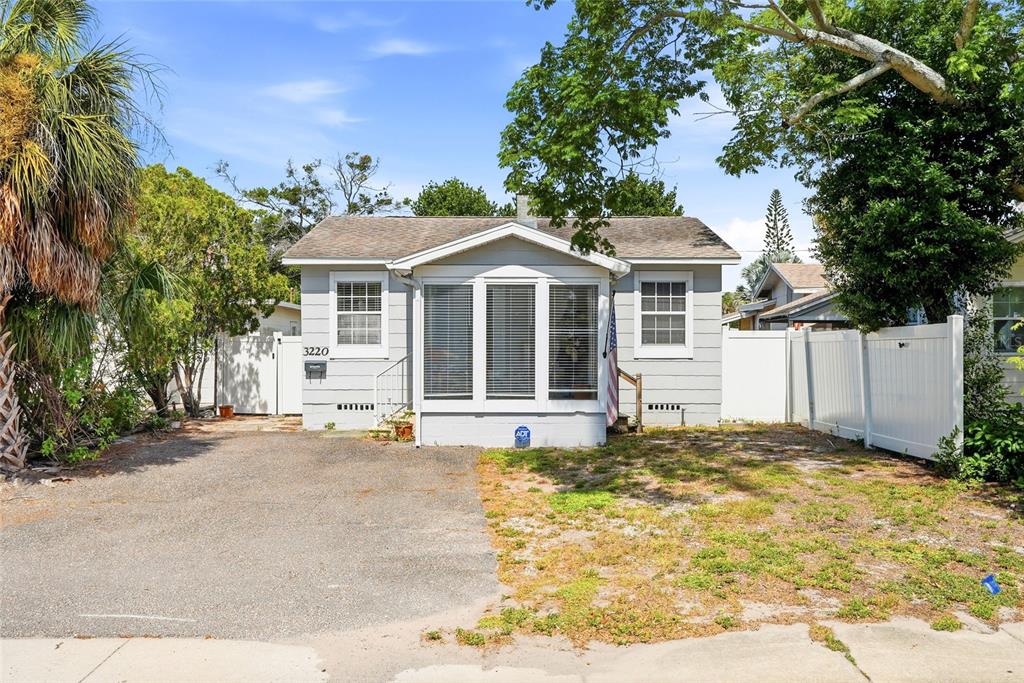 A single-story house with light gray siding, a front sunroom, and a paved driveway — 3220 16TH STREET N, ST PETERSBURG, FL