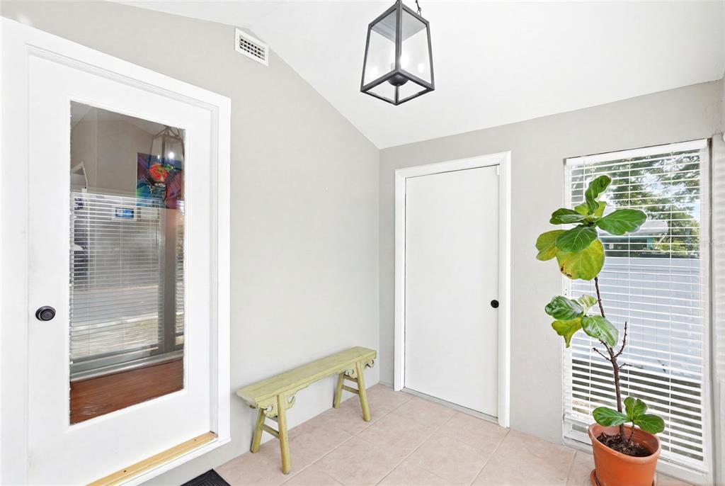 A bright entryway features a light green bench, a potted fiddle leaf fig, and tile flooring — 3220 16TH STREET N, ST PETERSBURG, FL