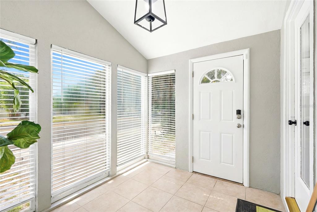 A bright entryway features tiled floors, large windows with blinds, and a white front door — 3220 16TH STREET N, ST PETERSBURG, FL