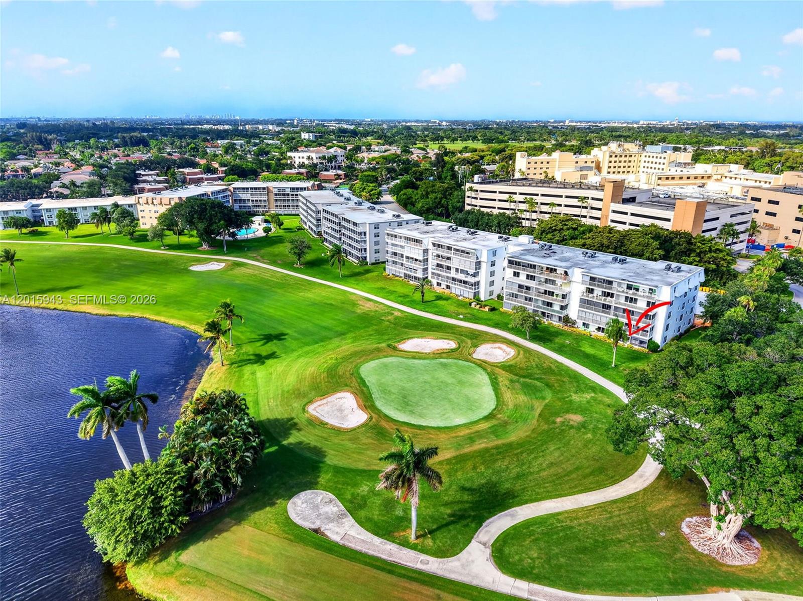 An aerial view shows a multi-story apartment building overlooking a golf course and lake — 300 John F Kennedy Dr # 101, Atlantis FL 33462, ATLANTIS, FL