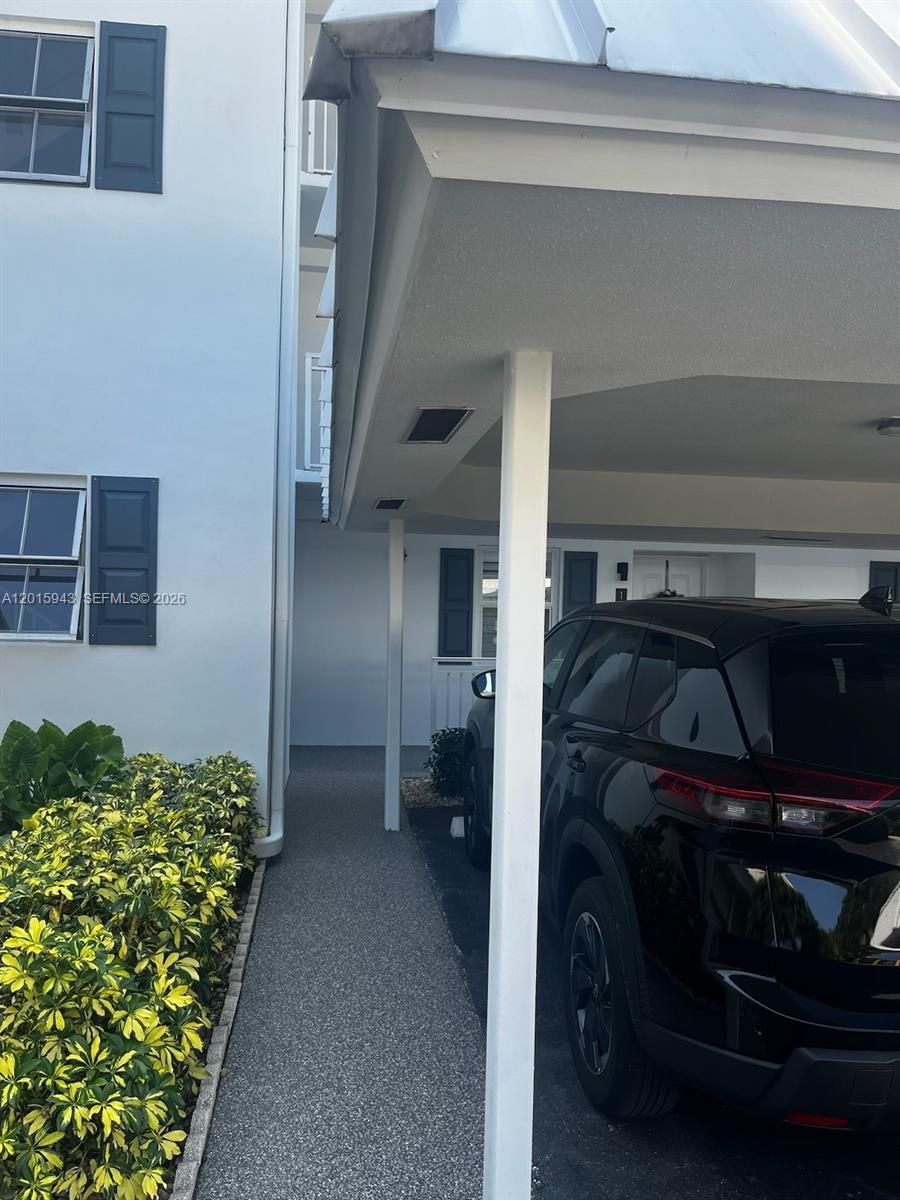 A black SUV is parked under a covered carport next to a white building — 300 John F Kennedy Dr # 101, Atlantis FL 33462, ATLANTIS, FL
