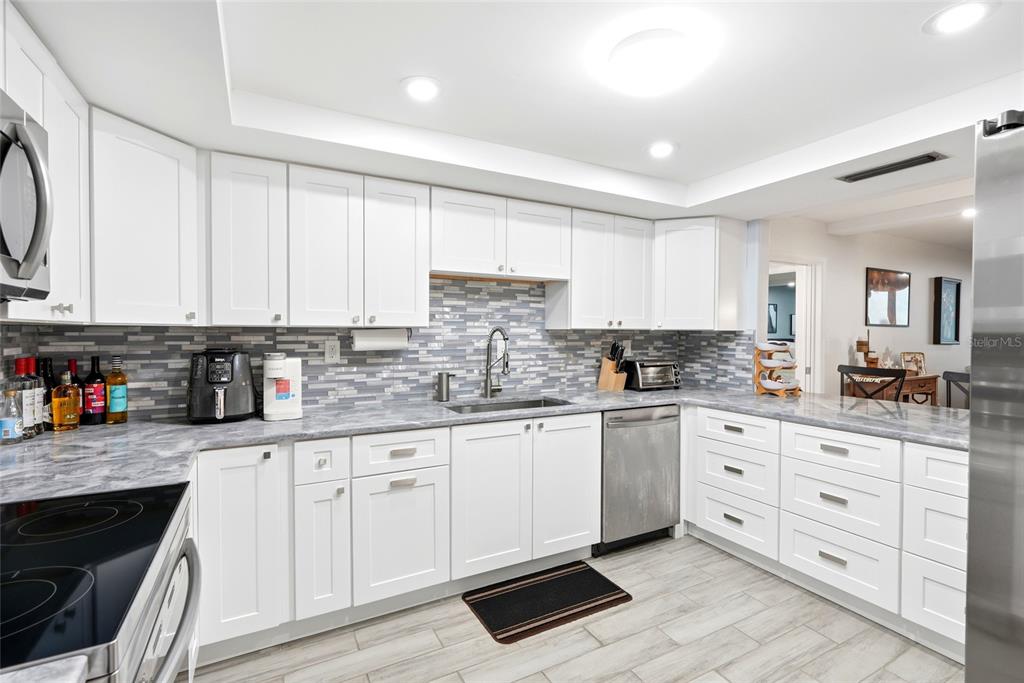 A view from a hallway looking into a kitchen and a dining area with balcony — 17920 GULF BOULEVARD UNIT 1502, ST PETERSBURG, FL