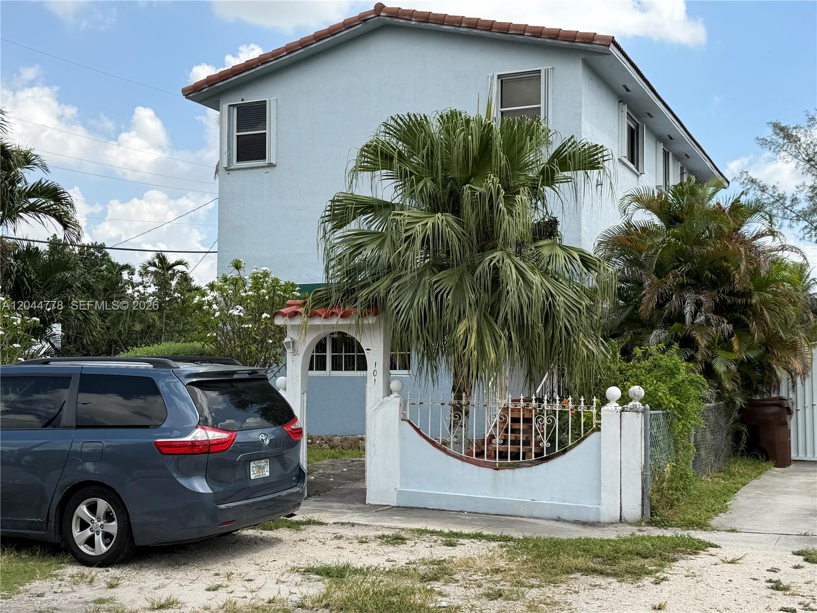 A two-story light blue house features a palm tree and a gated entrance — 101 E 51st Pl # 0, Hialeah FL 33013, HIALEAH, FL