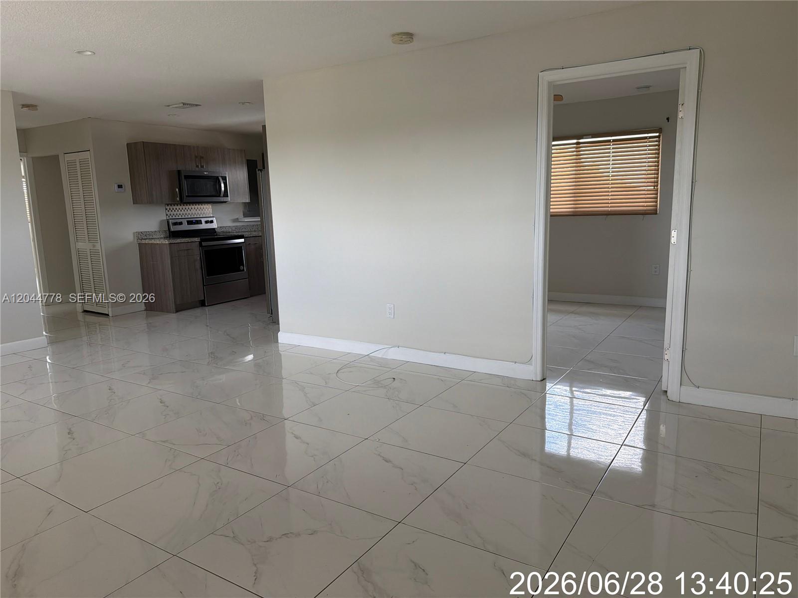 An interior view shows a kitchen with dark cabinets and a room with tiled floors — 101 E 51st Pl # 0, Hialeah FL 33013, HIALEAH, FL