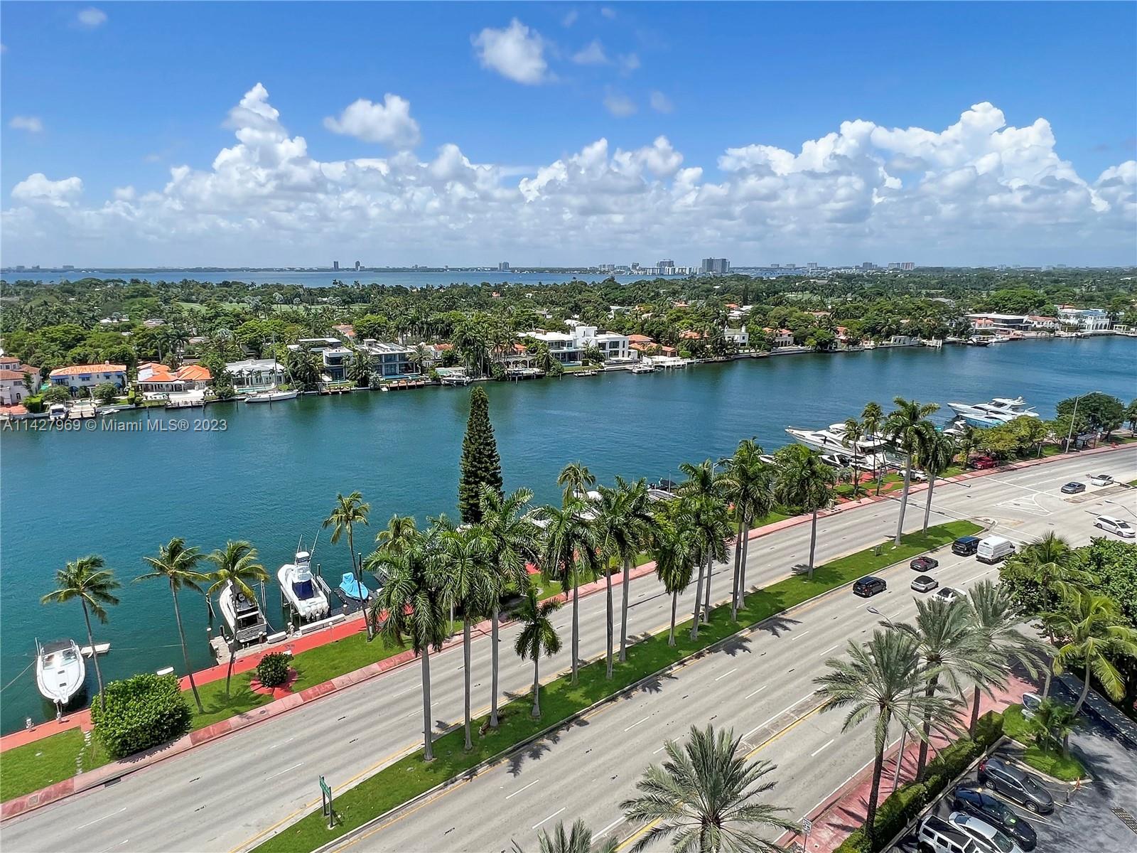 An elevated view shows a road lined with palm trees beside a canal with boats — 5151 Collins Ave # 1523, Miami Beach FL 33140, MIAMI BEACH, FL