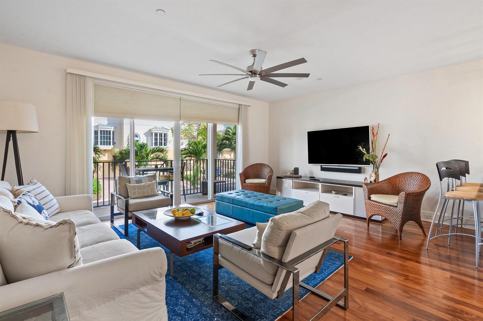 A living room with hardwood floors, a blue area rug, and a sliding glass door — 464 Juno Dunes Way, Juno Beach FL 33408, JUNO BEACH, FL