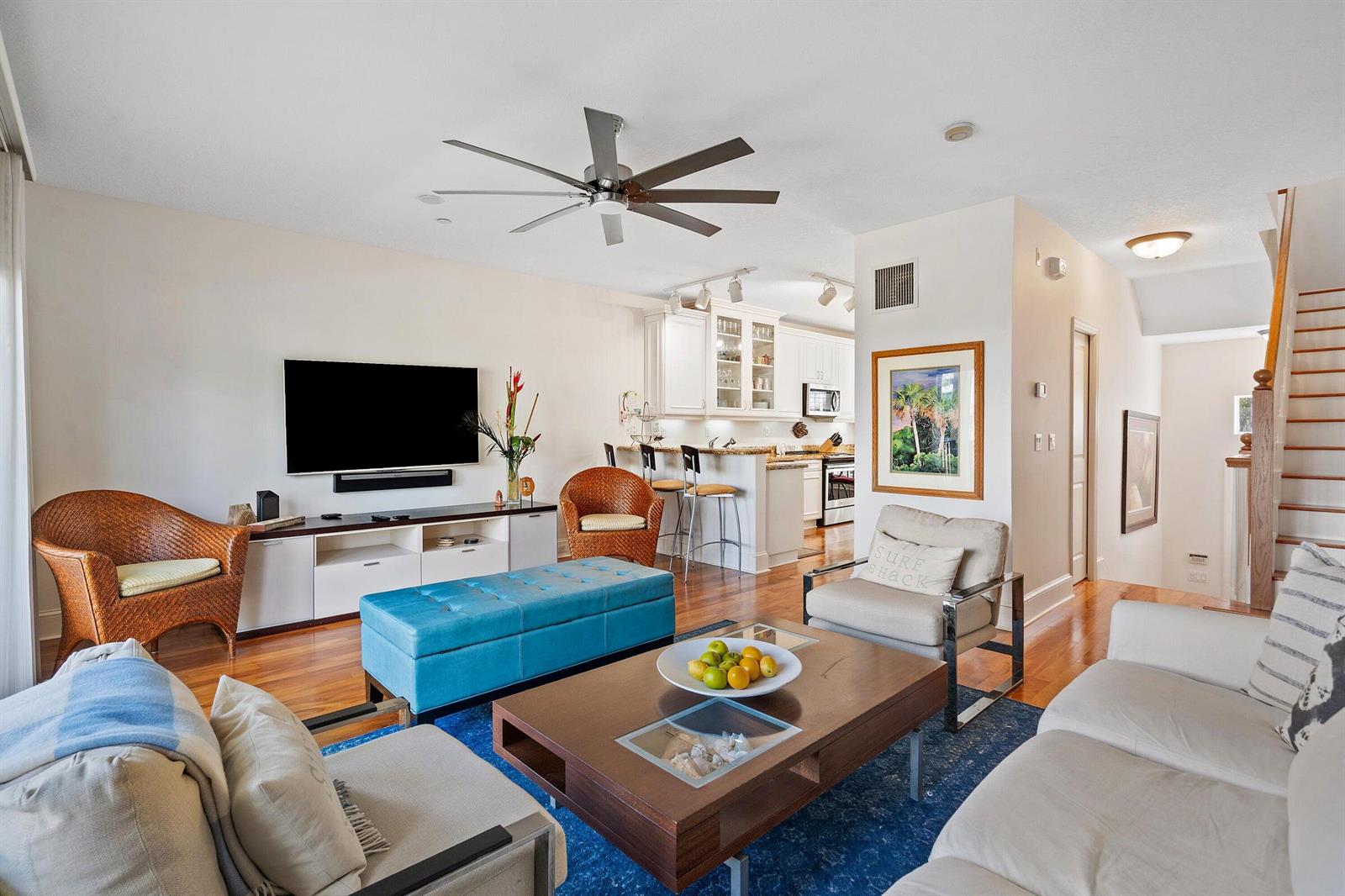 A living room with a blue ottoman, wooden coffee table, and an open kitchen area — 464 Juno Dunes Way, Juno Beach FL 33408, JUNO BEACH, FL