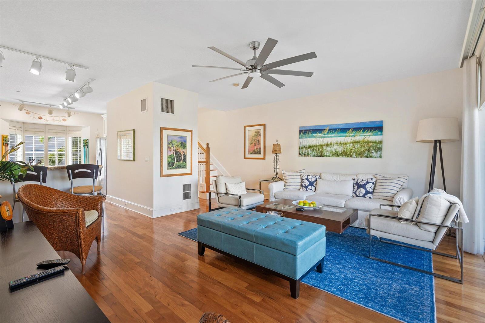 A living room with hardwood floors, a blue ottoman, and a large ceiling fan — 464 Juno Dunes Way, Juno Beach FL 33408, JUNO BEACH, FL