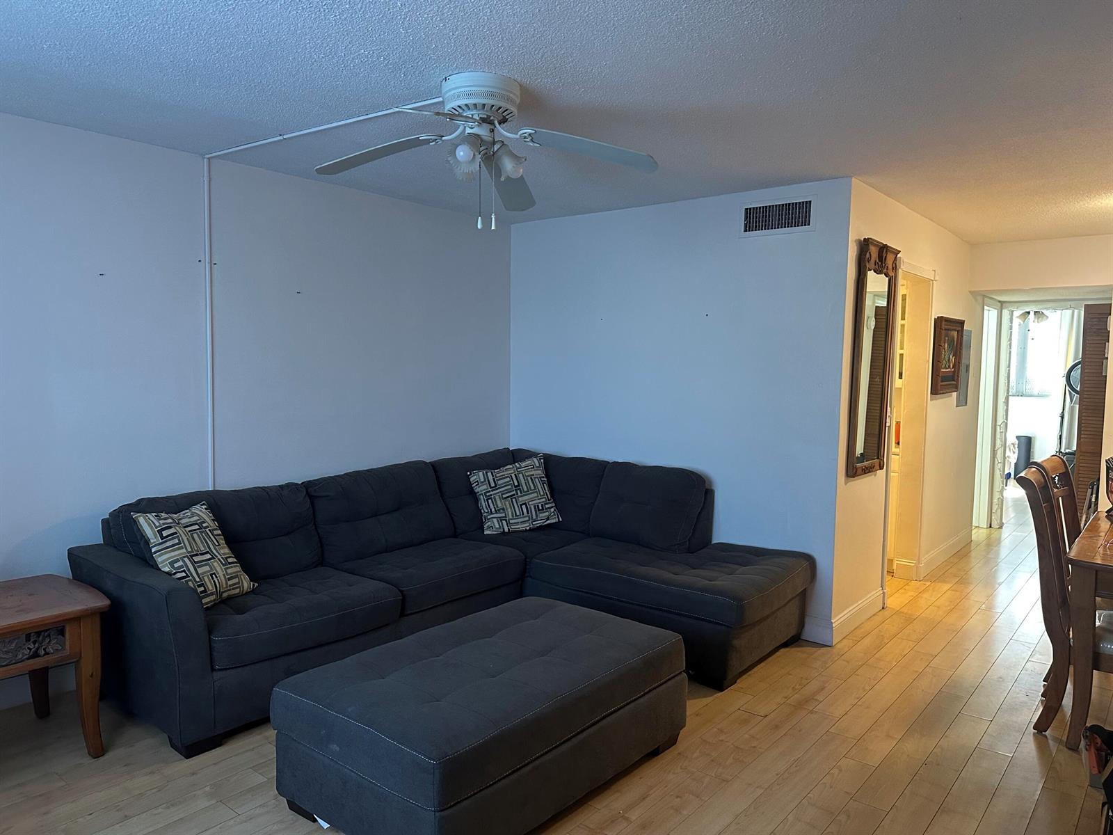 A living room features a gray sectional sofa, a matching ottoman, and light wood flooring — 2565 S Ocean Boulevard # C, Palm Beach FL 33480, PALM BEACH, FL