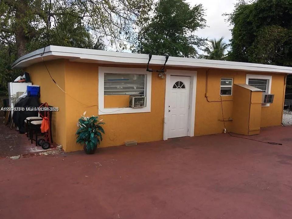 A yellow exterior wall features a white door, two windows, and a red concrete patio — 10040 NW 8th Ave, Miami FL 33150, MIAMI, FL