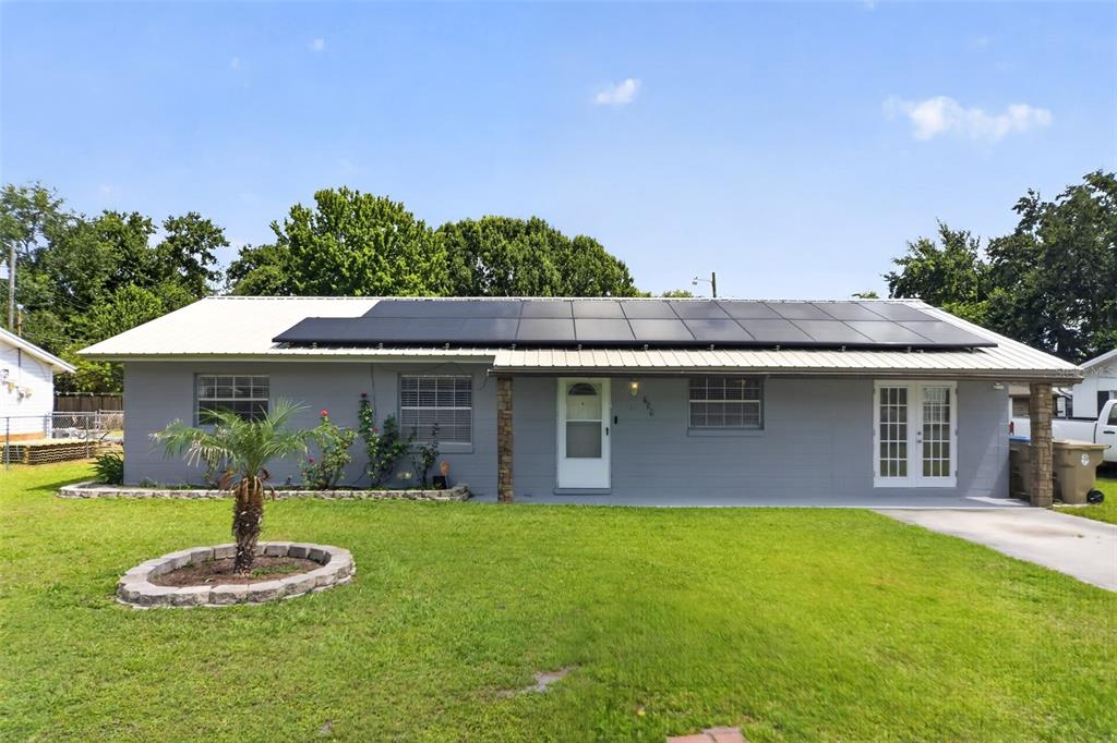 A single-story gray house with a white metal roof and solar panels — 755 PARK LANE, KISSIMMEE, FL