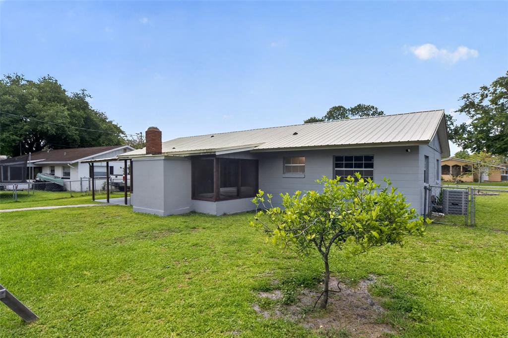 The exterior of a gray, single-story house with a metal roof and a screened porch — 755 PARK LANE, KISSIMMEE, FL