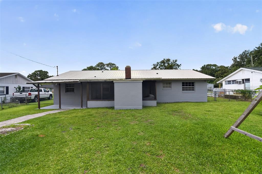 The exterior of a single-story house features a metal roof, gray siding, and a chimney — 755 PARK LANE, KISSIMMEE, FL