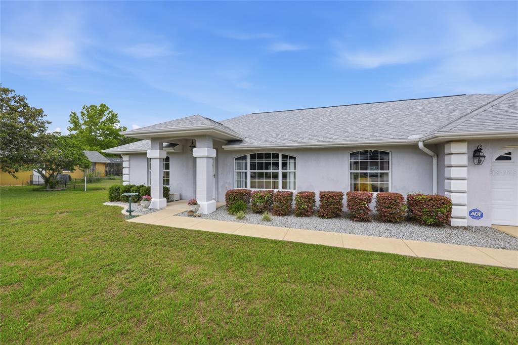 A single-story house with a gray exterior, a covered entryway, and a landscaped front yard — 14460 SE 98TH COURT, SUMMERFIELD, FL