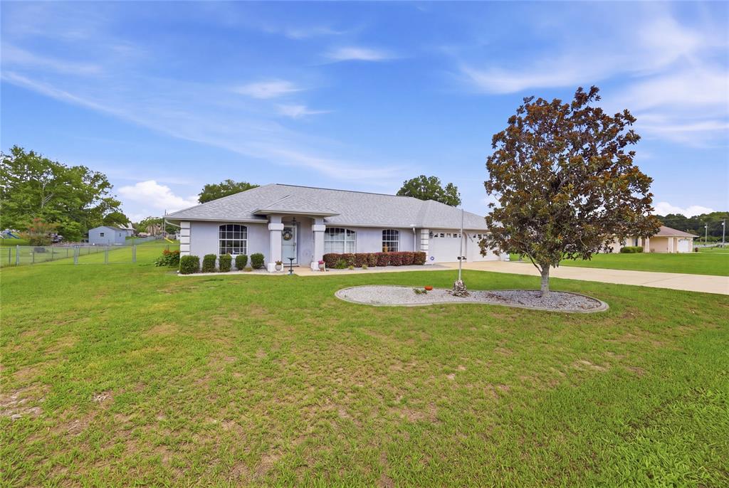 A single-story house with a gray roof and a large tree in the front yard — 14460 SE 98TH COURT, SUMMERFIELD, FL