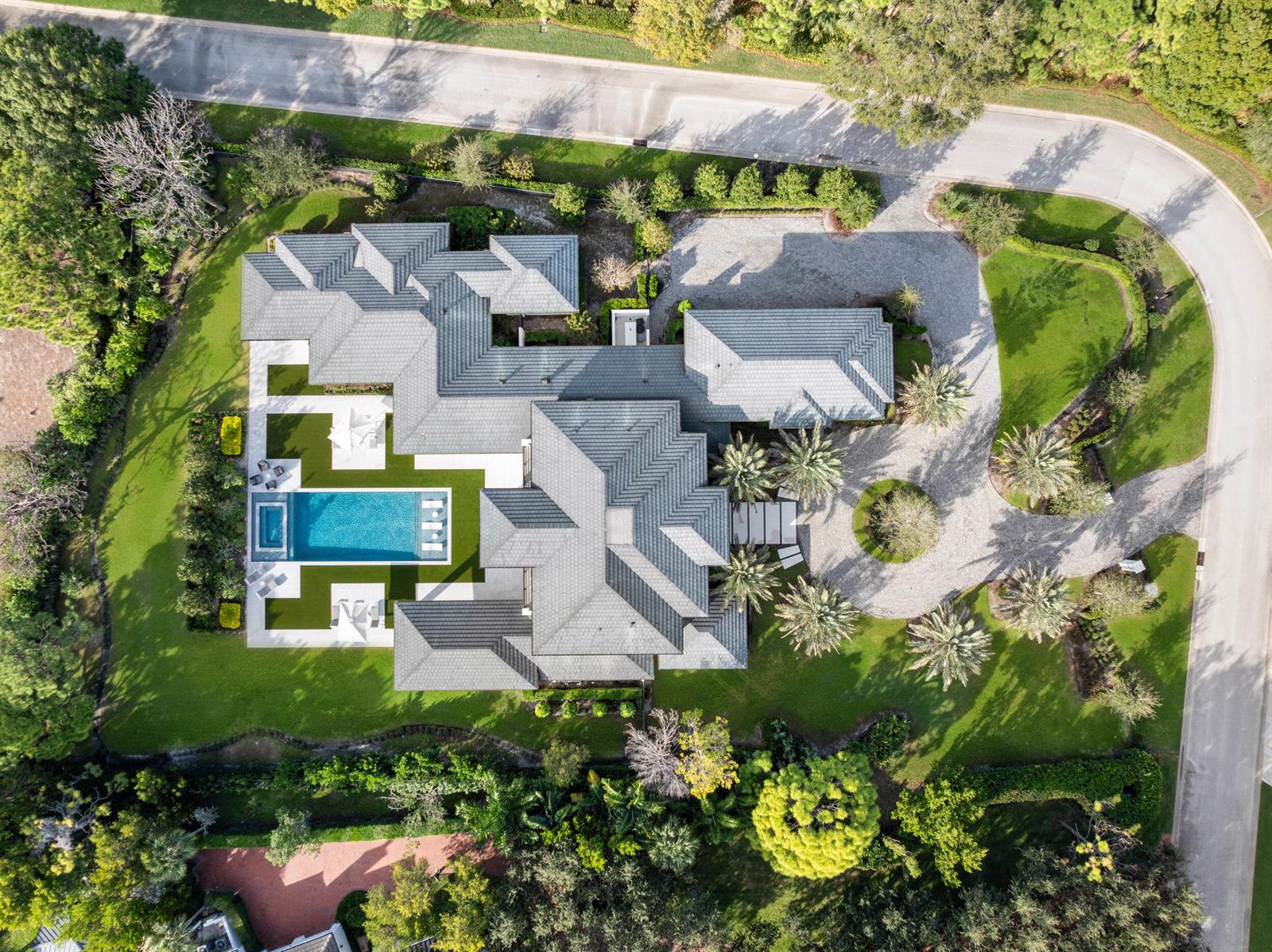 An aerial view shows a large house with a grey tiled roof, pool, and driveway — 210 Bears Club Drive, Jupiter FL 33477, JUPITER, FL