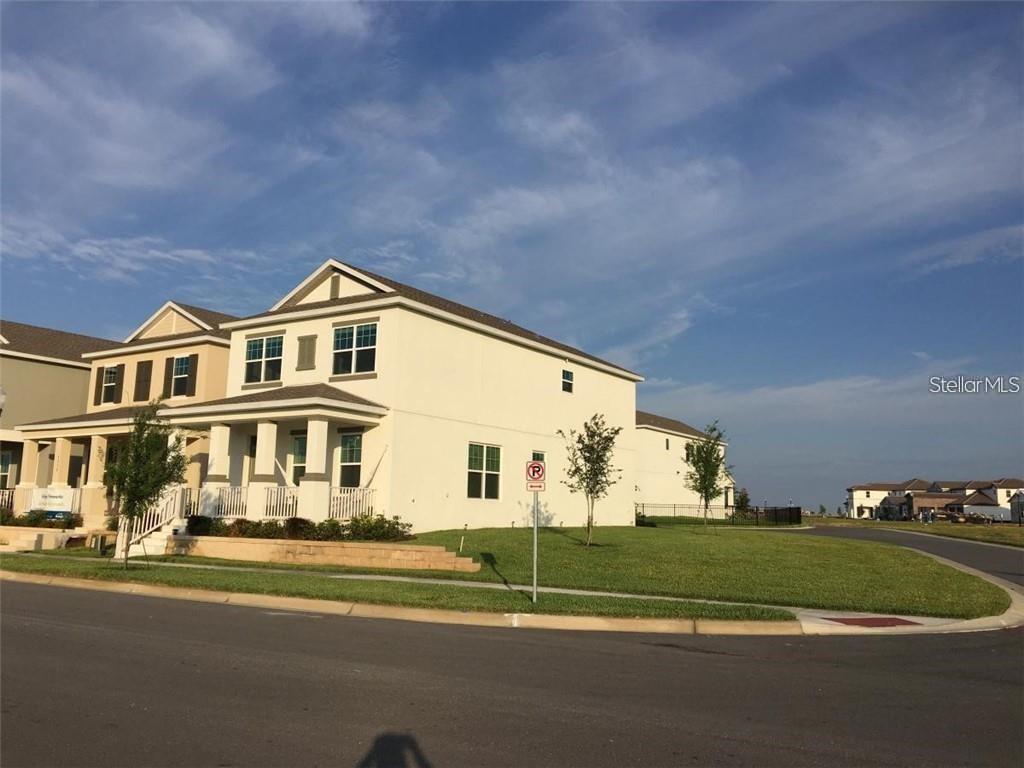 A two-story beige house with a wrap-around porch sits on a corner lot — 9350 WOODCRANE DRIVE, WINTER GARDEN, FL