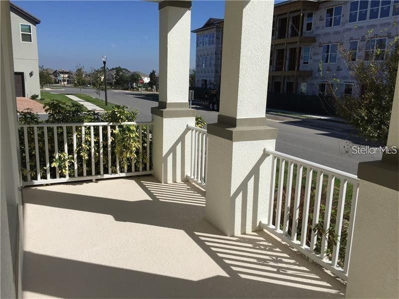 A covered porch with white railings and columns overlooks a street and nearby buildings — 9350 WOODCRANE DRIVE, WINTER GARDEN, FL