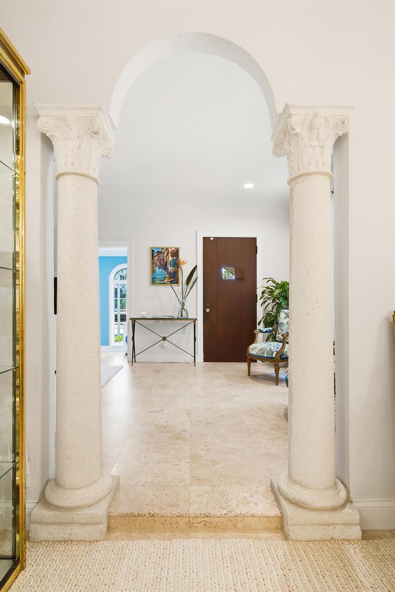 An arched entryway with stone columns leads into a foyer with tile flooring and doors — 235 Nottingham Boulevard, West Palm Beach FL 33405, WEST PALM BEACH, FL