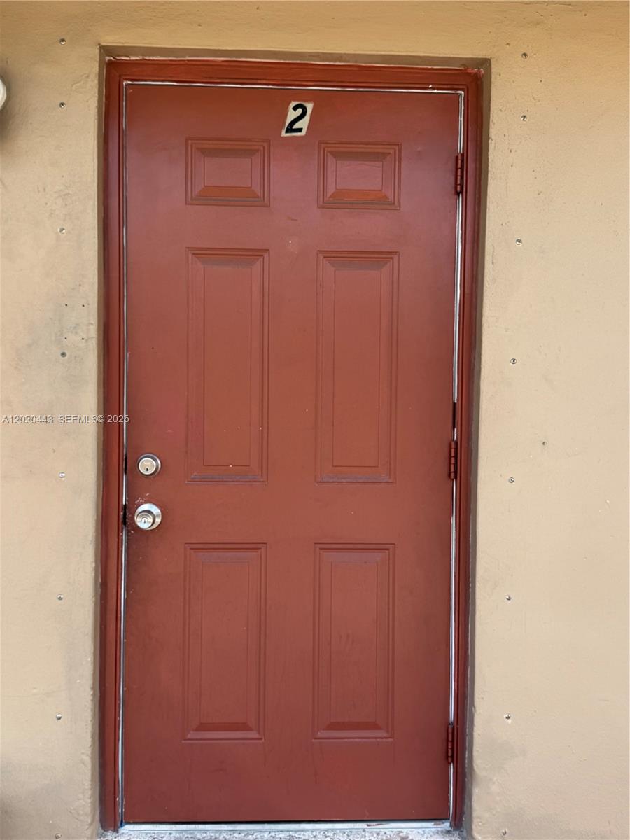 A red door with the number two is set into a plain tan wall — 2924 NW 132nd Ter # 2, Opa-Locka FL 33054, OPA-LOCKA, FL