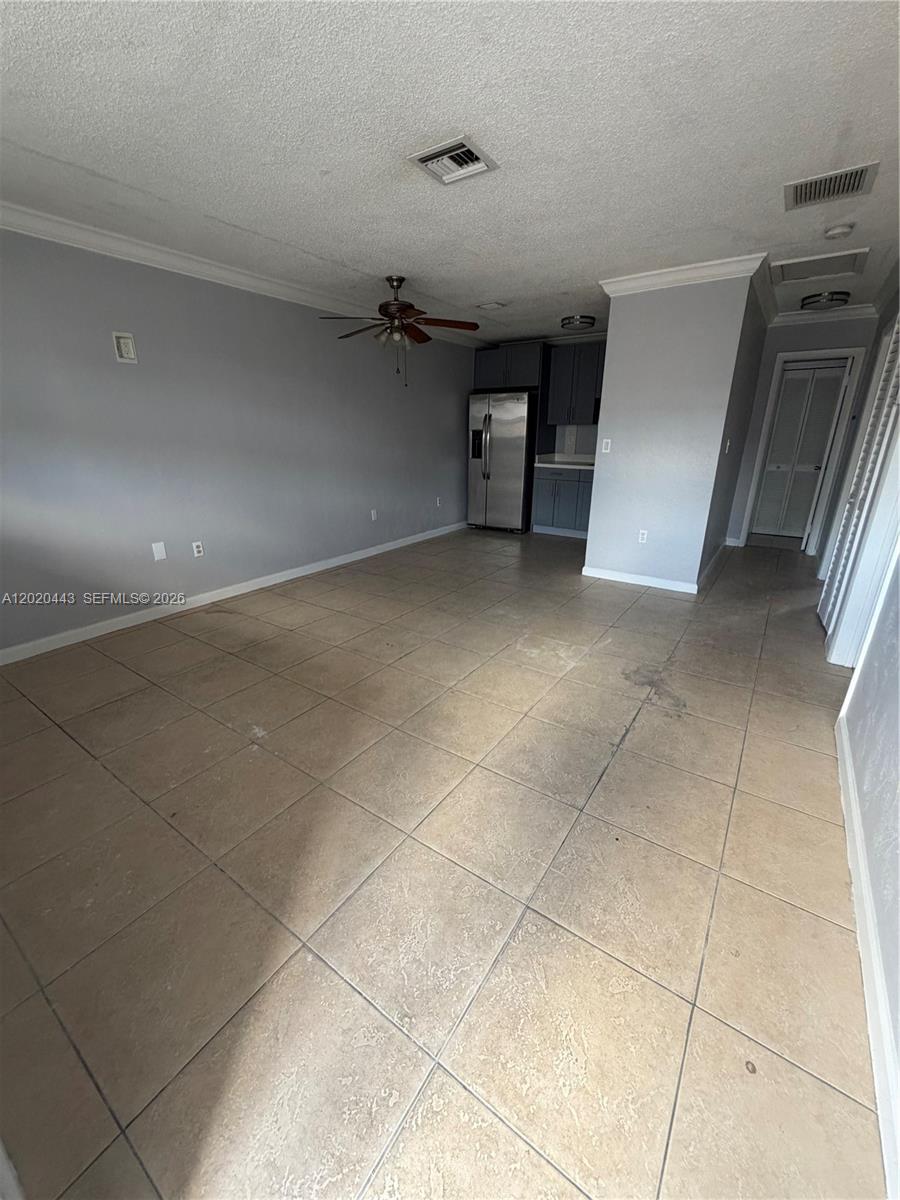This room features light gray walls, large beige floor tiles, and an open kitchen area — 2924 NW 132nd Ter # 2, Opa-Locka FL 33054, OPA-LOCKA, FL
