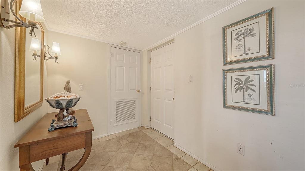 An entryway features a wooden console table, a wall mirror, and two framed palm prints — 9393 MIDNIGHT PASS ROAD UNIT P4, SARASOTA, FL