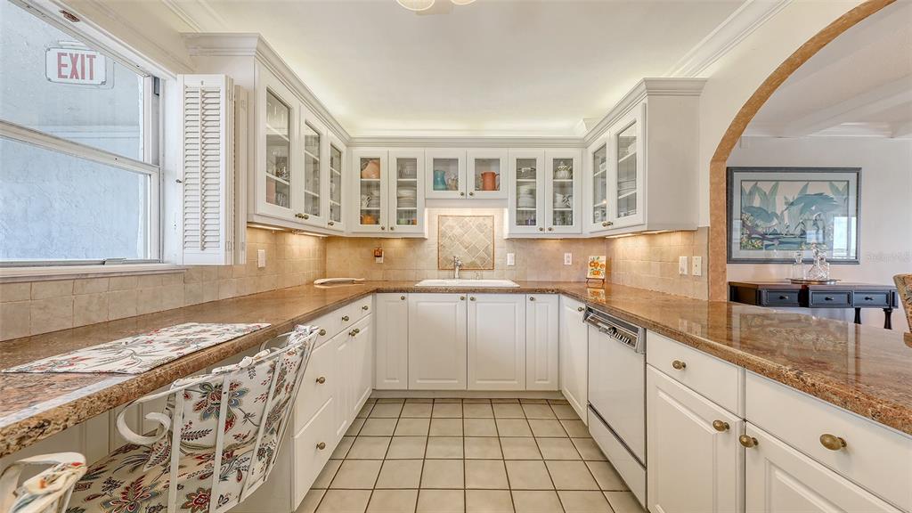 A kitchen with white cabinets, granite countertops, tile flooring, and a window with an exit sign — 9393 MIDNIGHT PASS ROAD UNIT P4, SARASOTA, FL