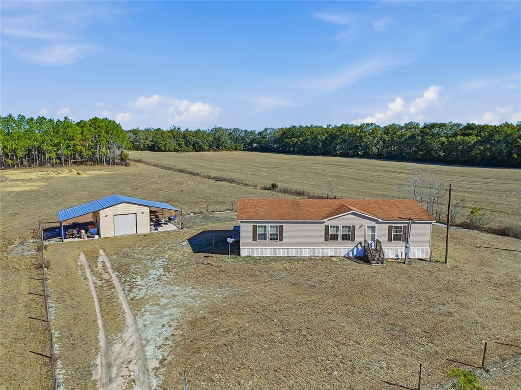 An aerial view shows a single-story house and a detached garage on a large field — 2400 NW 5TH STREET, BELL, FL