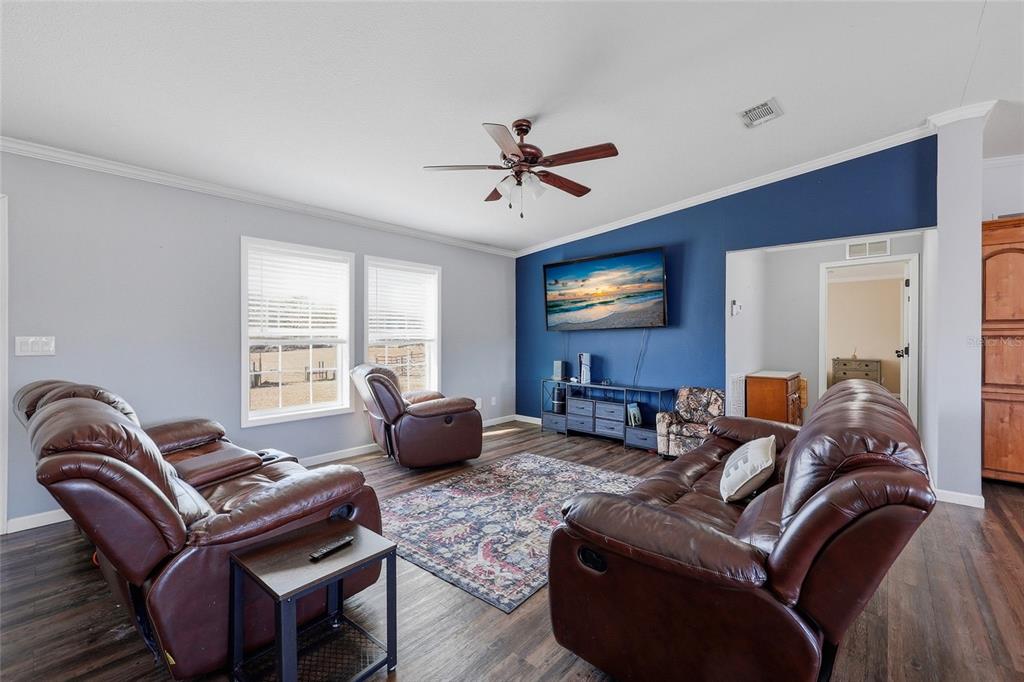 A living room features dark leather recliners, a blue accent wall with a television, and flooring — 2400 NW 5TH STREET, BELL, FL