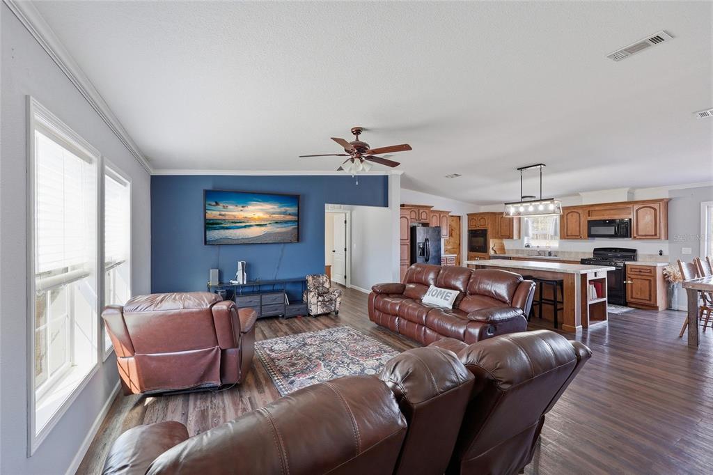 A living room with a blue accent wall and brown leather furniture opens to a kitchen — 2400 NW 5TH STREET, BELL, FL