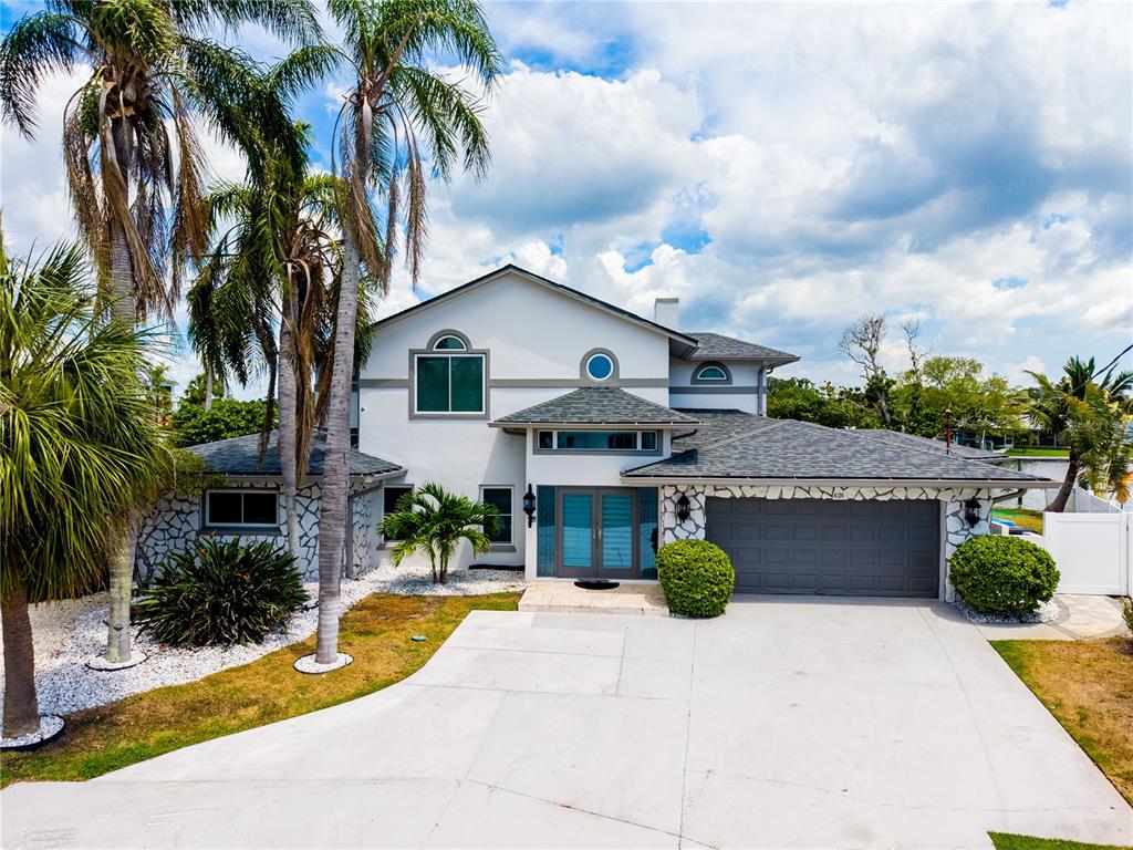 A two-story house with a gray garage, stone accents, and palm trees in the front yard — 4124 HARBOR CIRCLE S, LARGO, FL