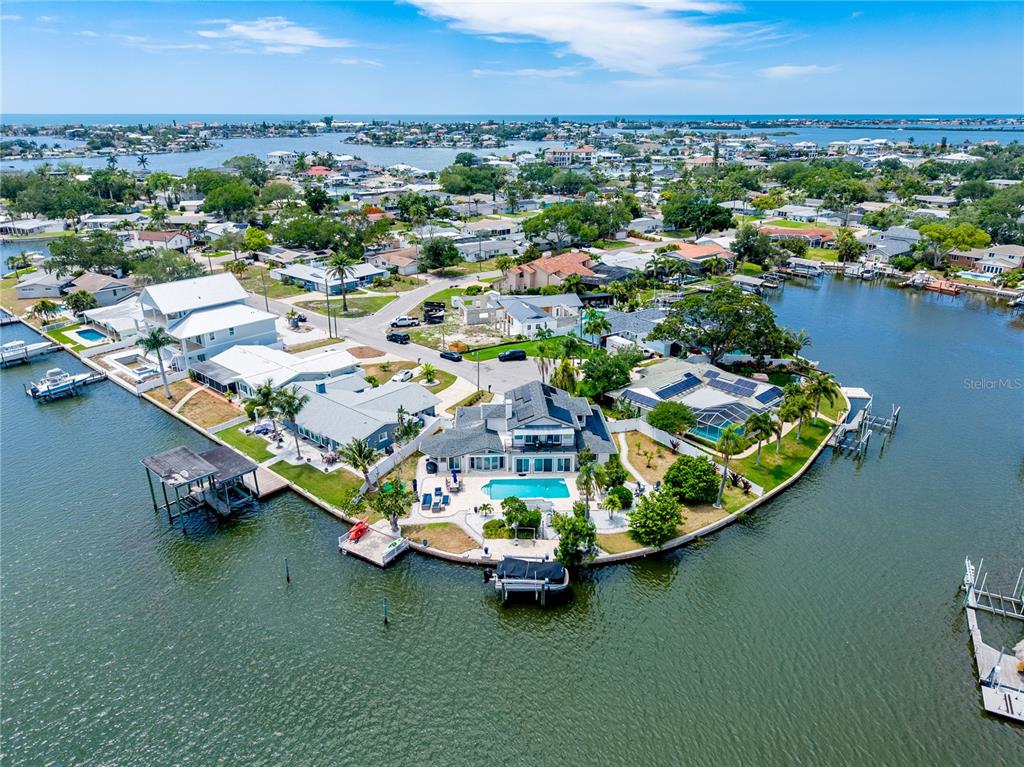 An aerial view shows a waterfront house with a pool on a point of land — 4124 HARBOR CIRCLE S, LARGO, FL